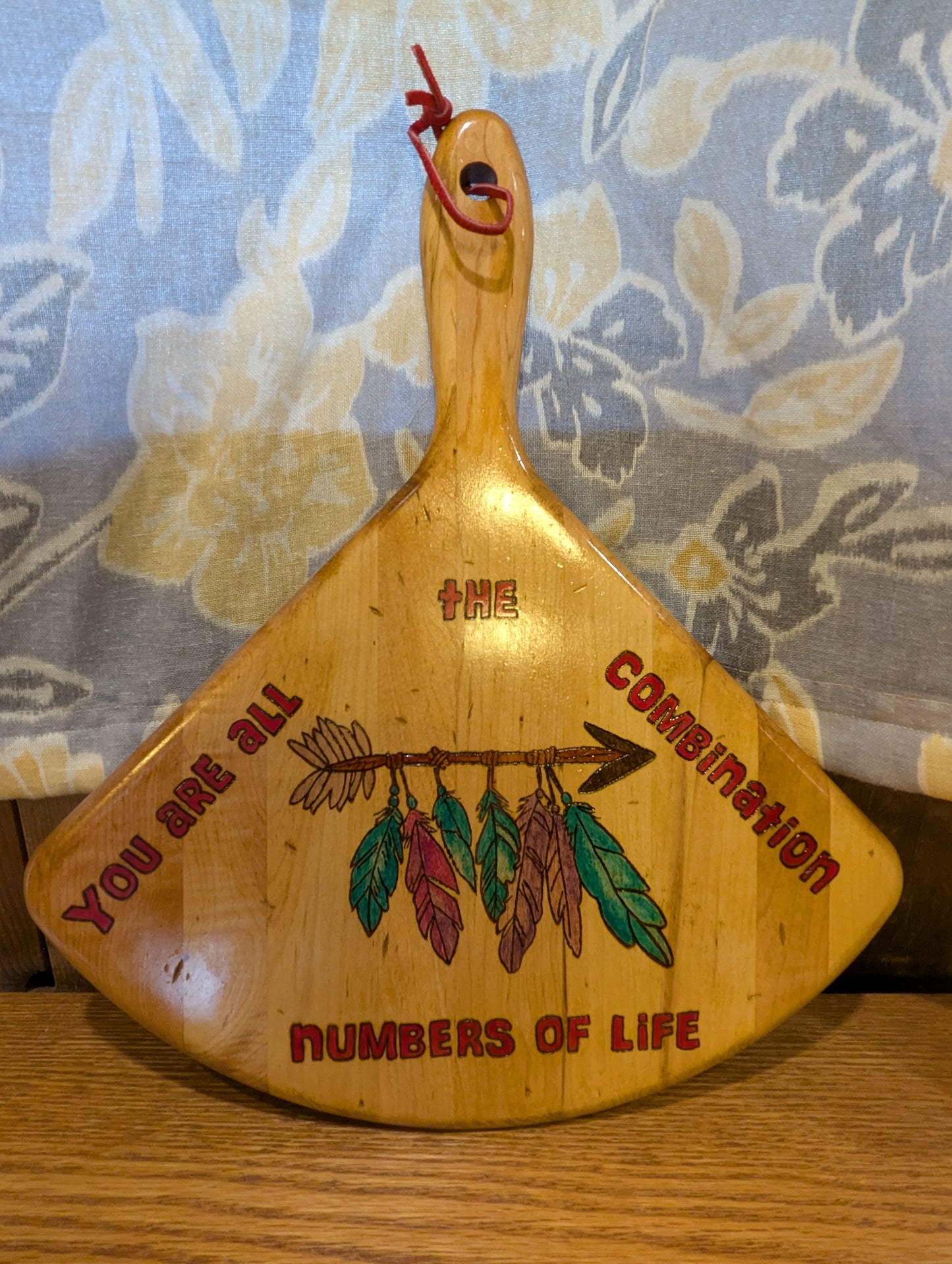 Wood-burned and hand painted decorative wooden bread paddle with 'You are all the combination numbers of life' text and decorative feather and arrow design.