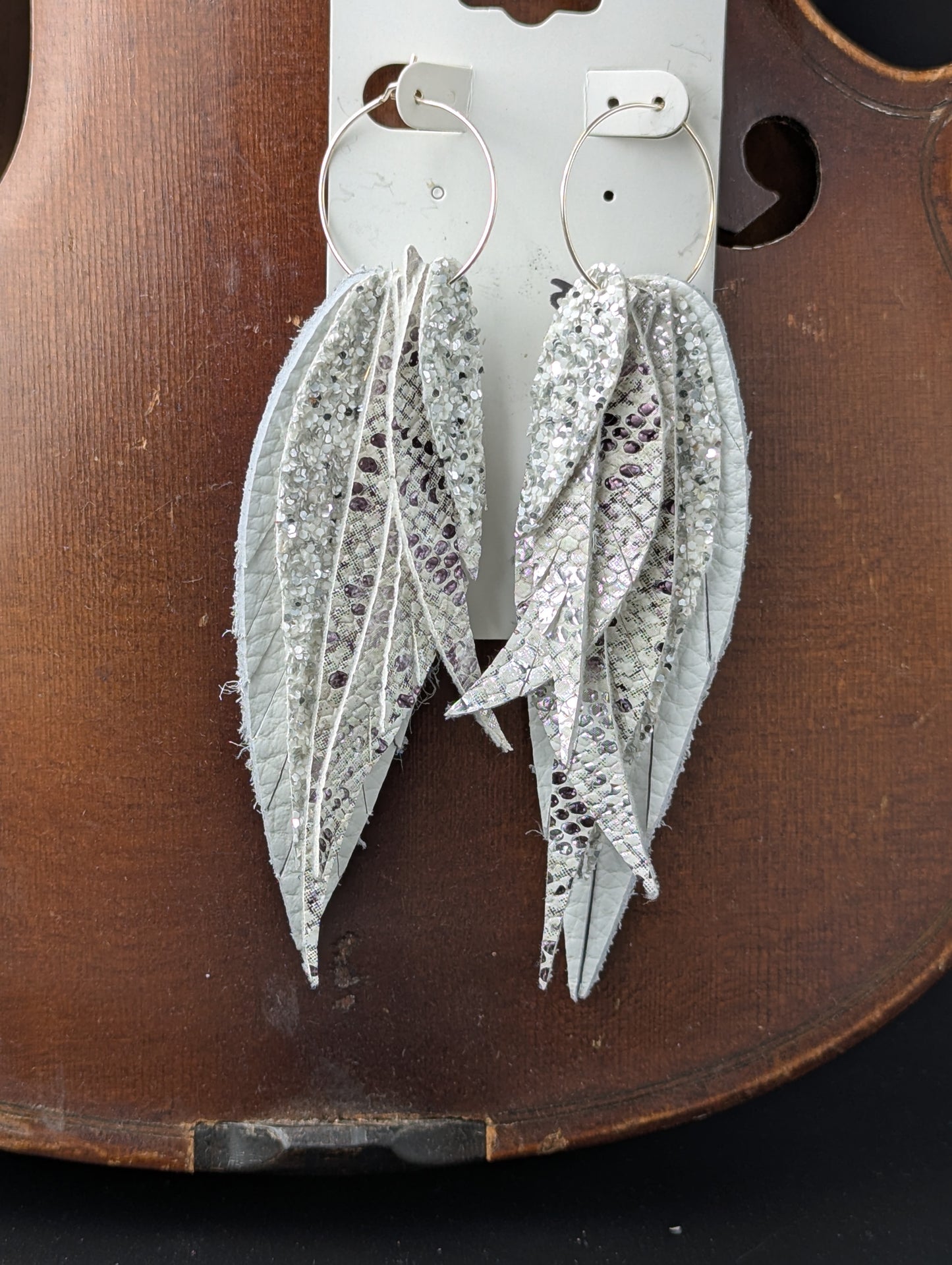 Leather feather shaped earrings. White, silver and black with silver hoops. 4.5 inches long.