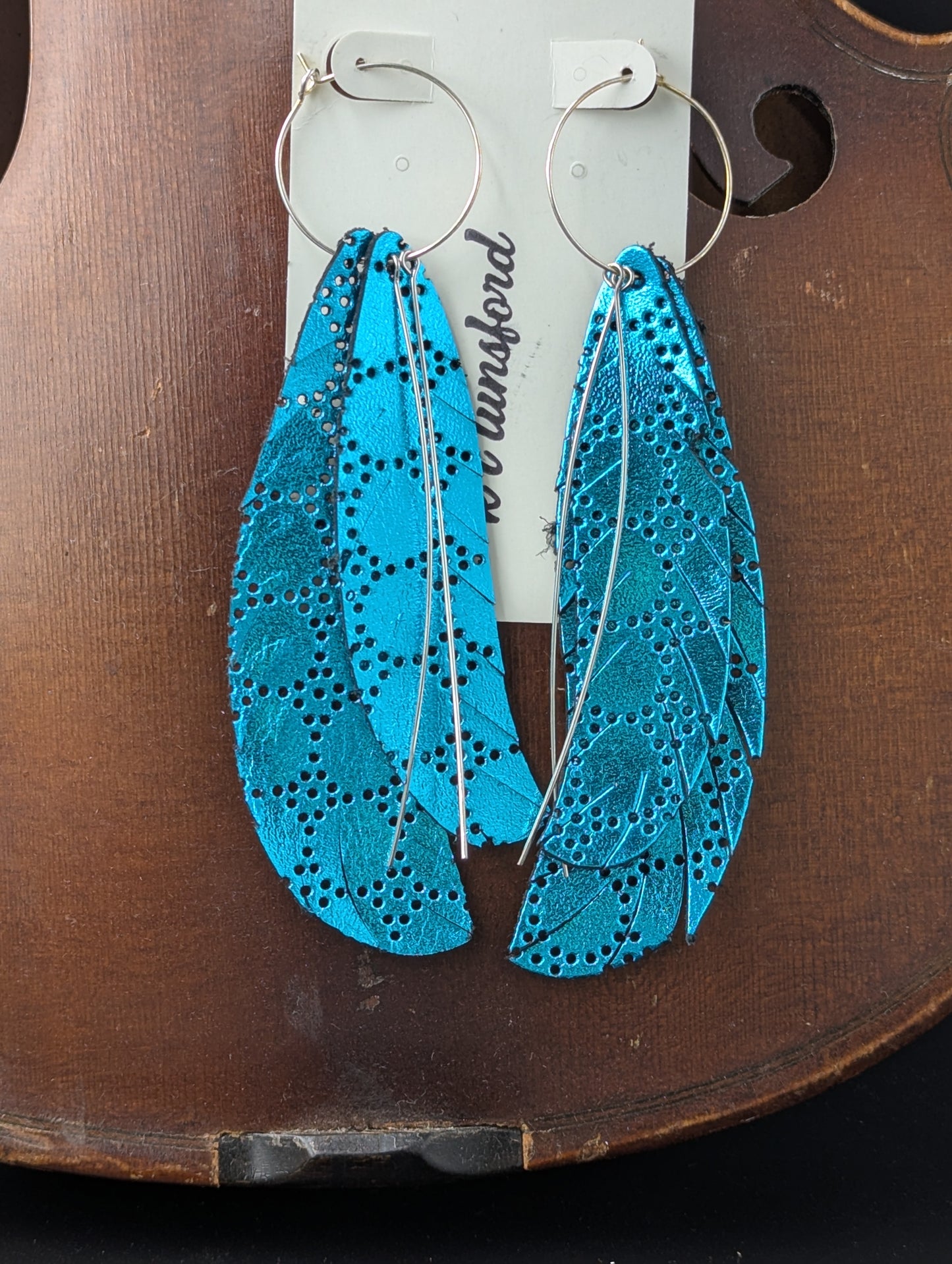 Leather earrings. Feather shaped, teal with delicate silver accents on silver hoops. 4.5 inches long.
