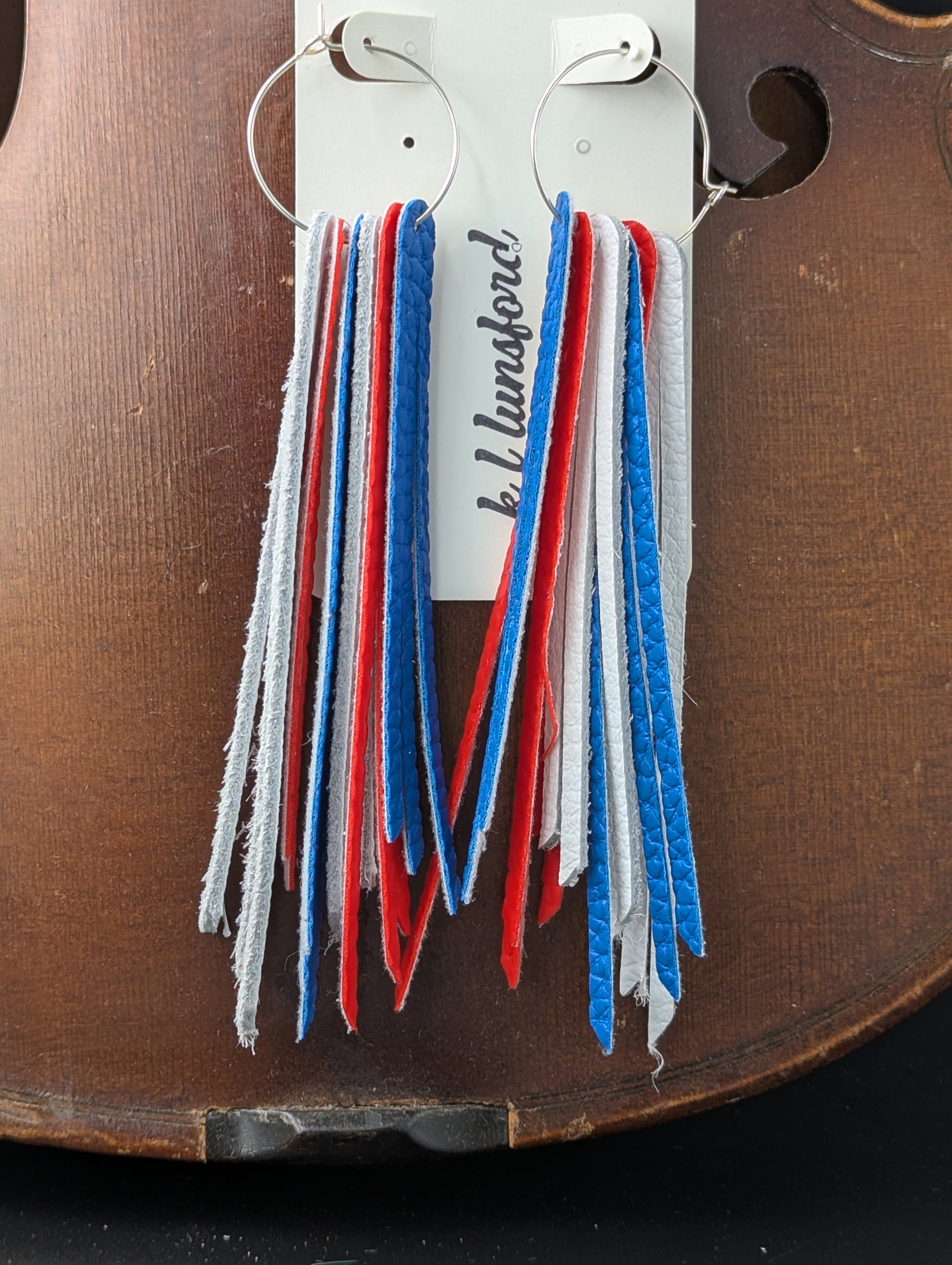 Leather earrings in red, white, and blue leather strips on hypoallergenic silver hoops. 5 inches in length.