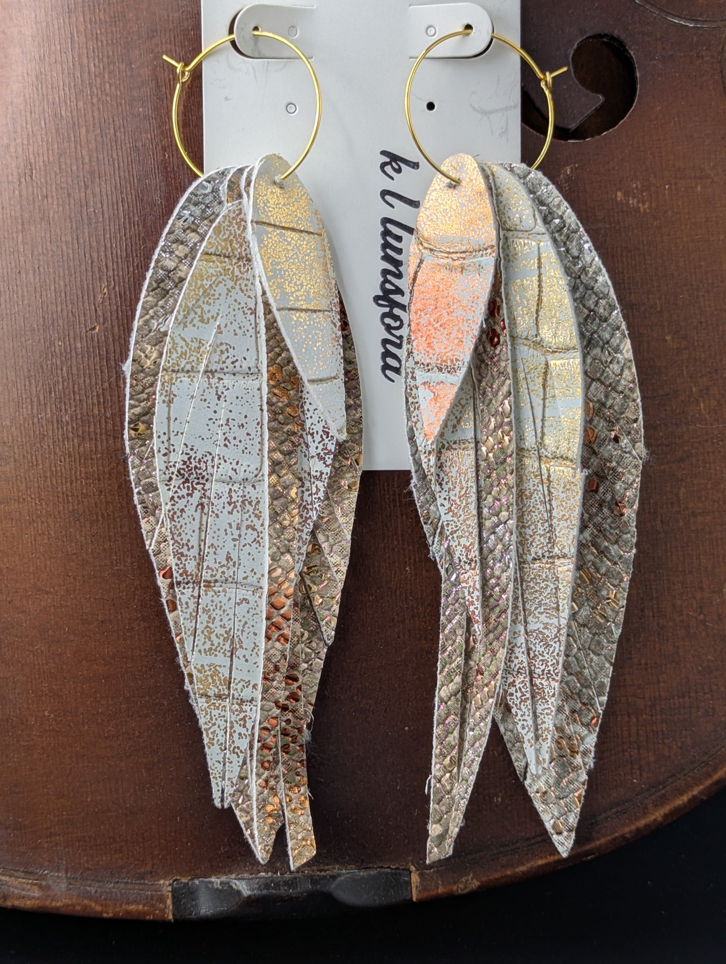 Vegan leather feather shaped dangle earrings. Bronze, gold, silver and white with gold hoops. 5.5 inches long.