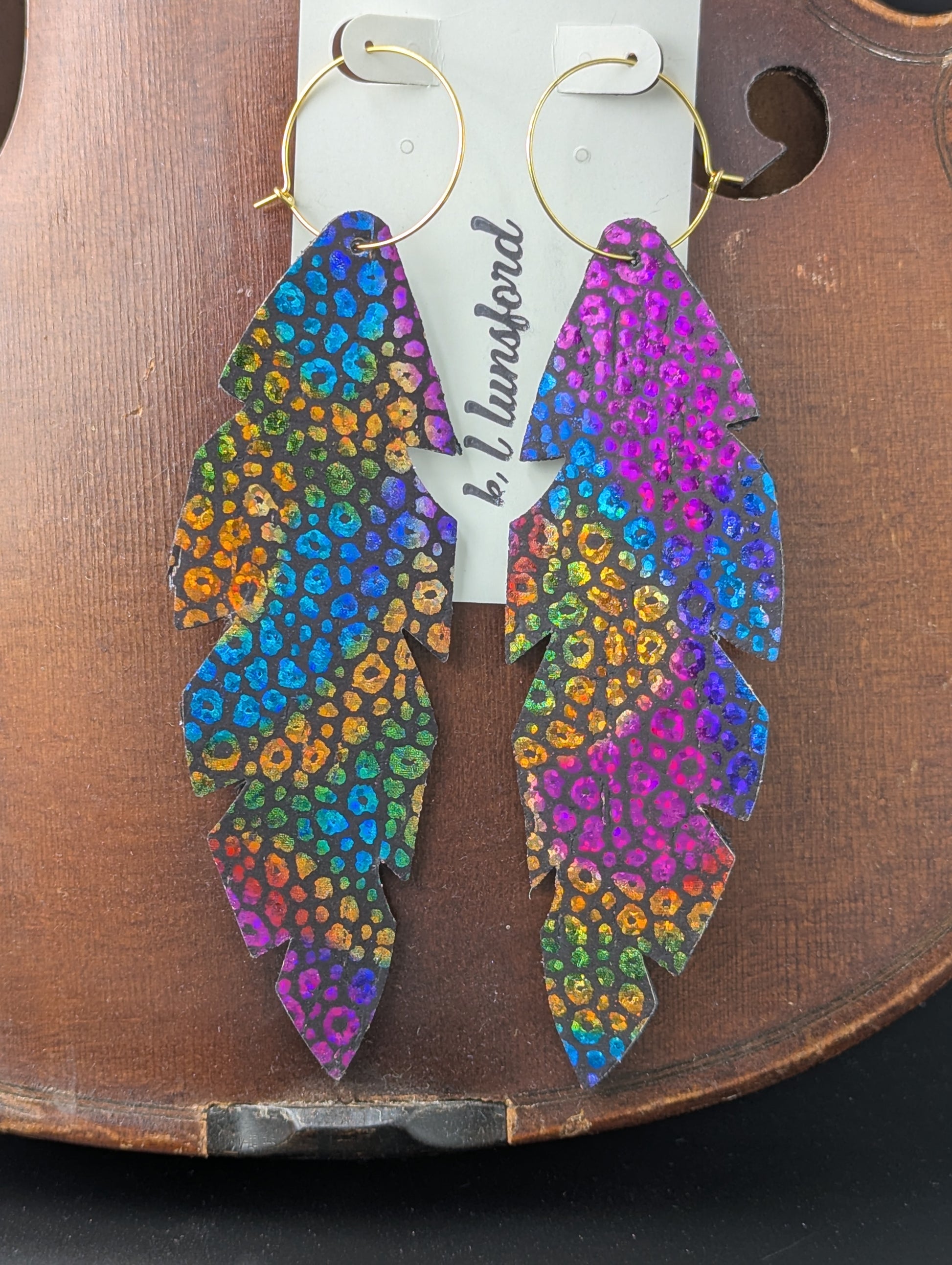 Colorful, feather shaped leather earrings with gold hoops. 5 inches long.