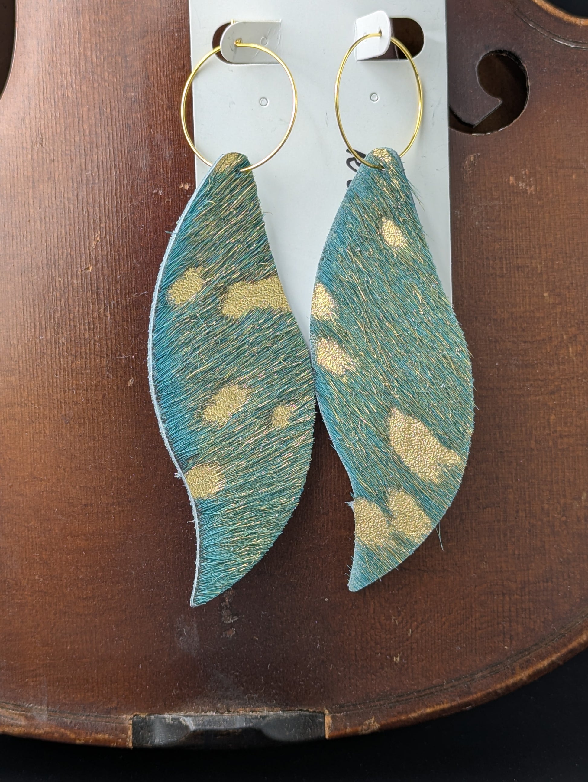 Genuine cow hide dyed teal, gold embossed with gold hoops. 4.5 inches