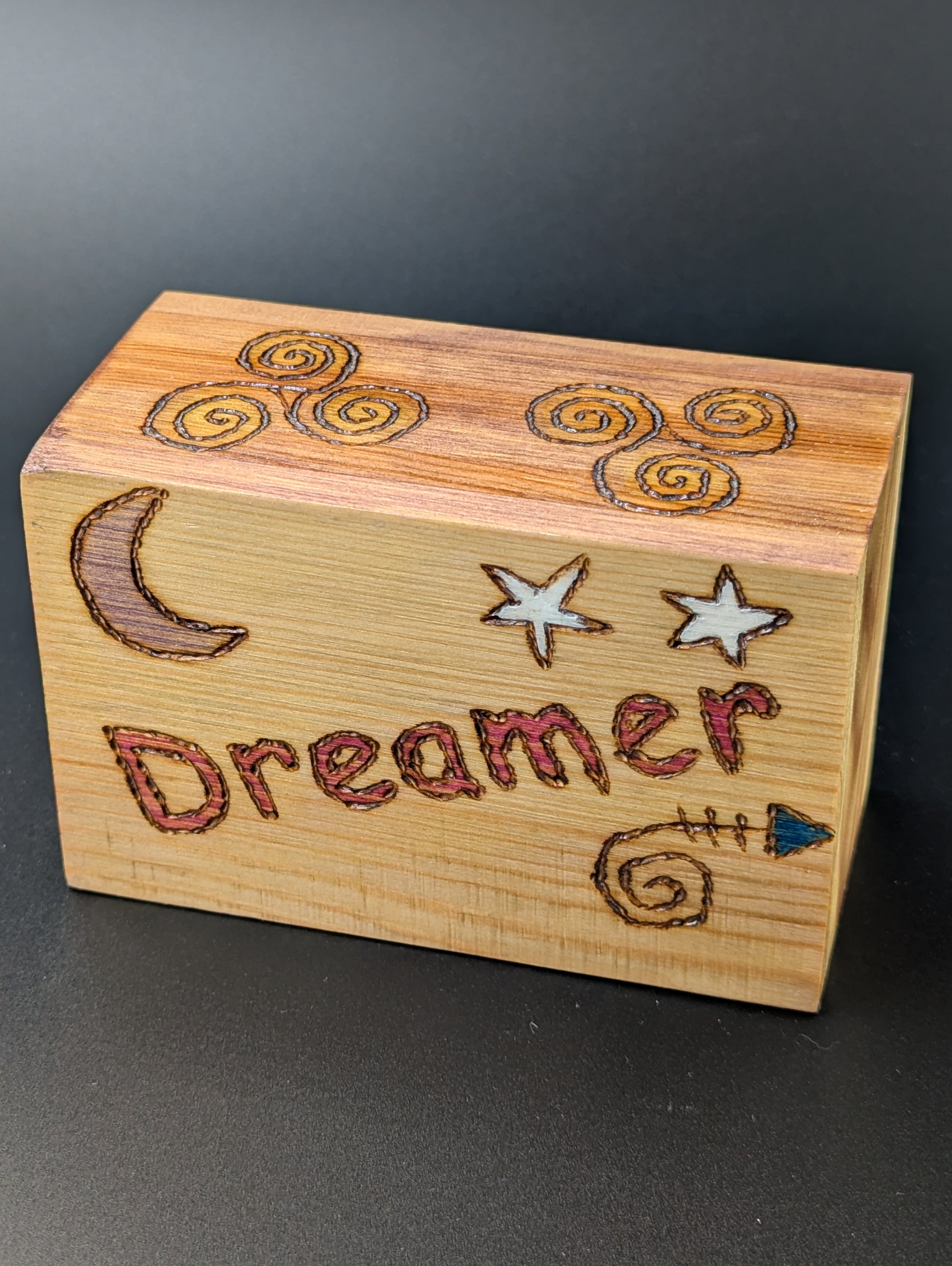 Wooden box with artistic wood-burned and hand painted design of the moon and stars surrounding the word "dreamer".