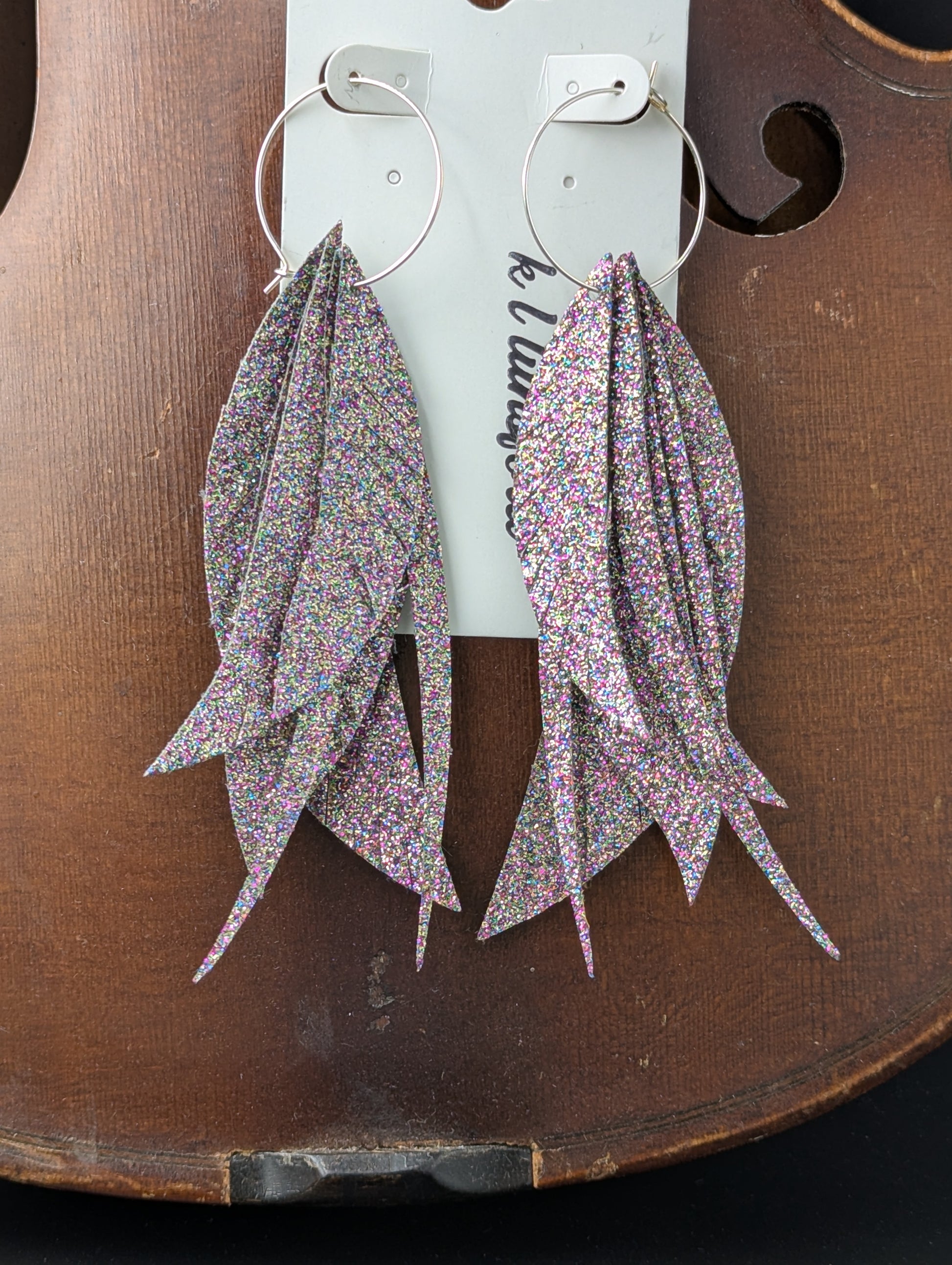 Iridescent sparkling feathers made from vegan leather on silver hoops. Very lightweight. 4 1/2 inches in length. 