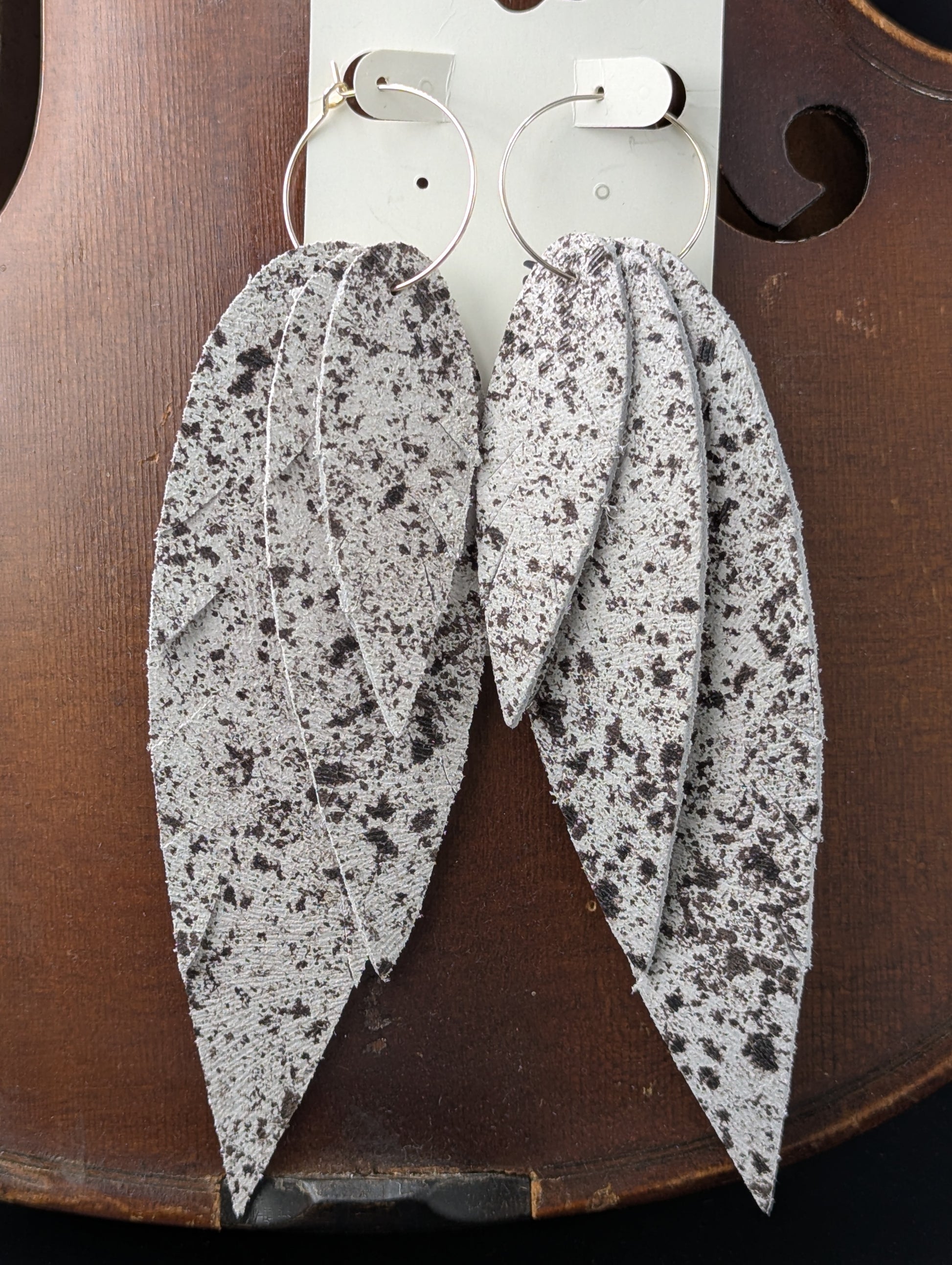 Leather, feather shaped earrings with silver hoops. White and black. 5.5 inches long.