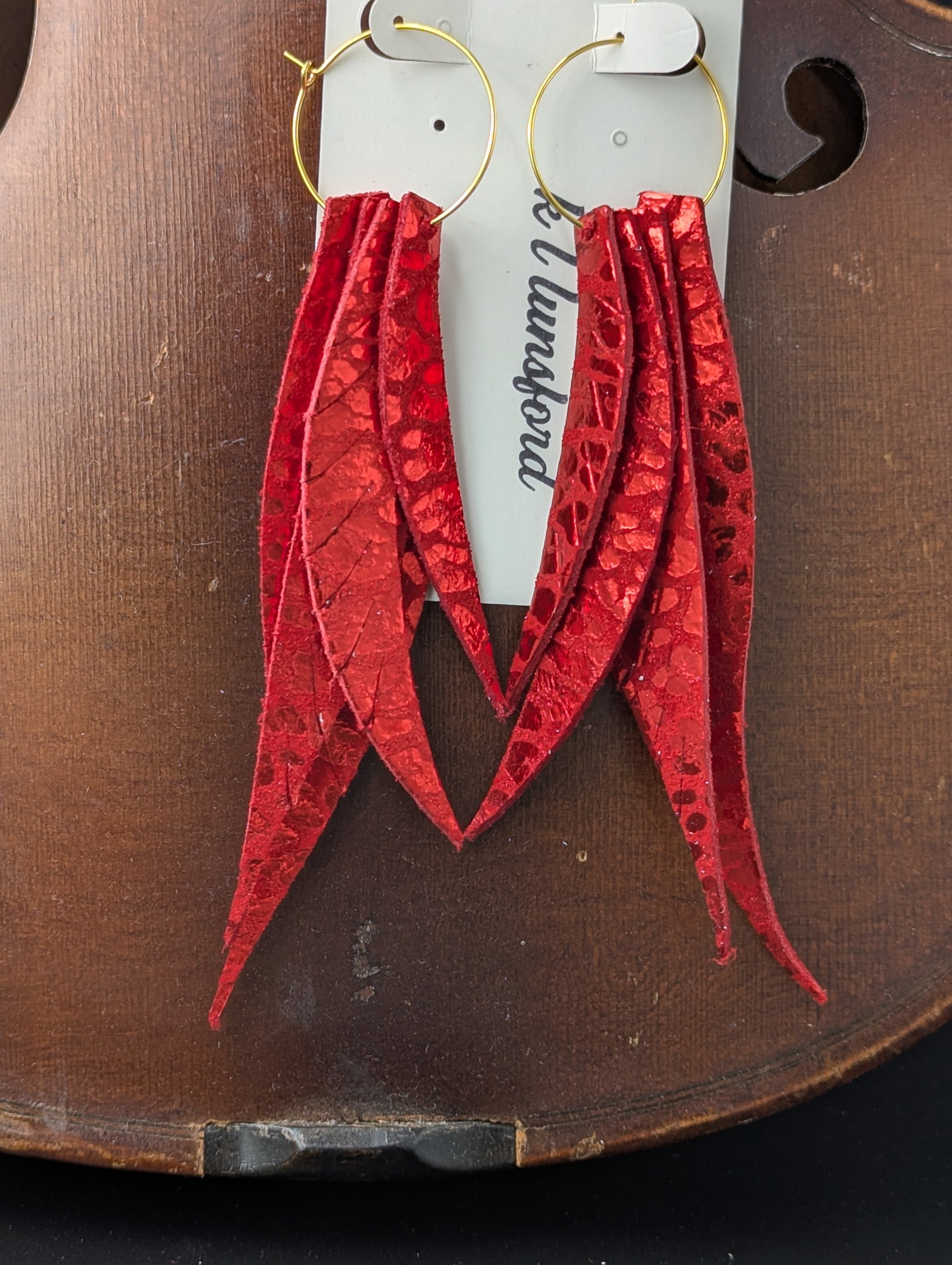 Leather leaf shaped earrings. Red with metallic red accents on gold hoops. 5 inches long.