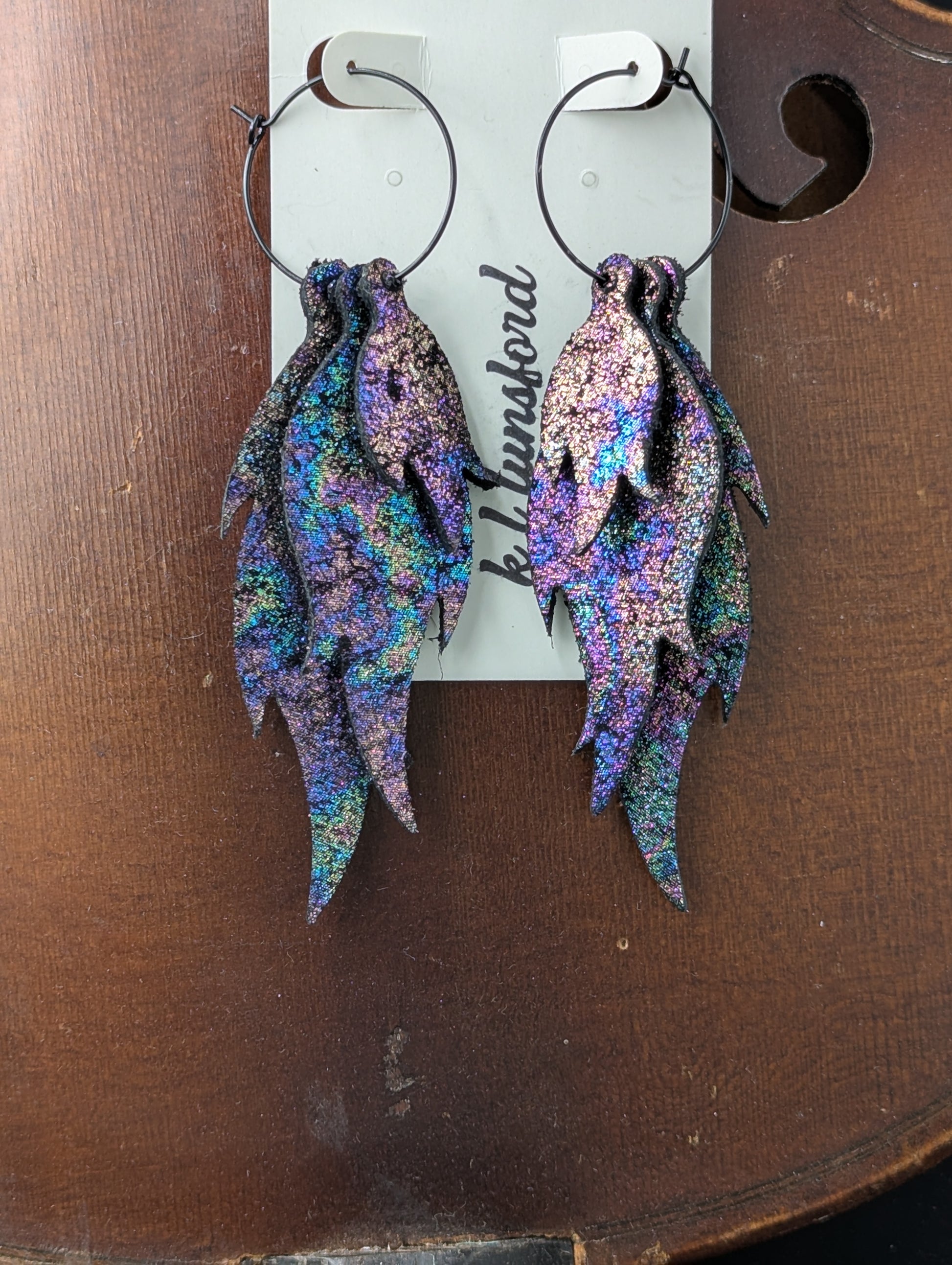 Leather flame shaped earrings. Vibrant iridescent sparkles on black leather with black hoops. 4 inches long.