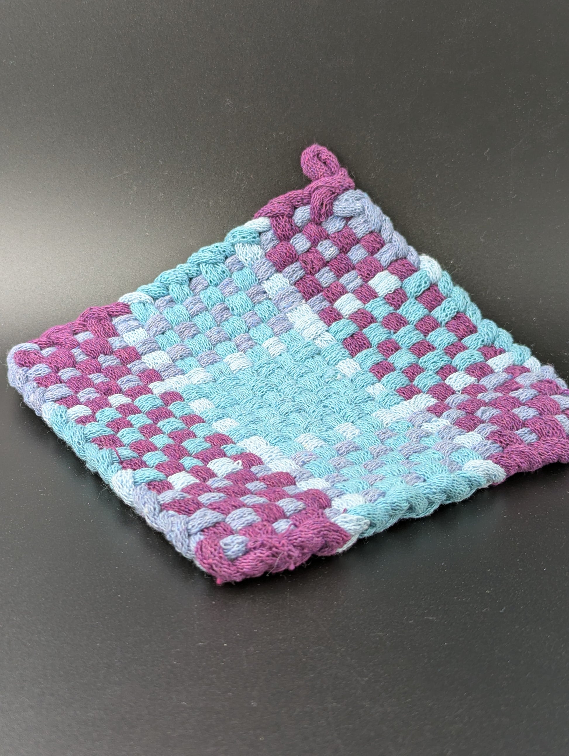 Hand woven pot holder in purple, blue and gray.
