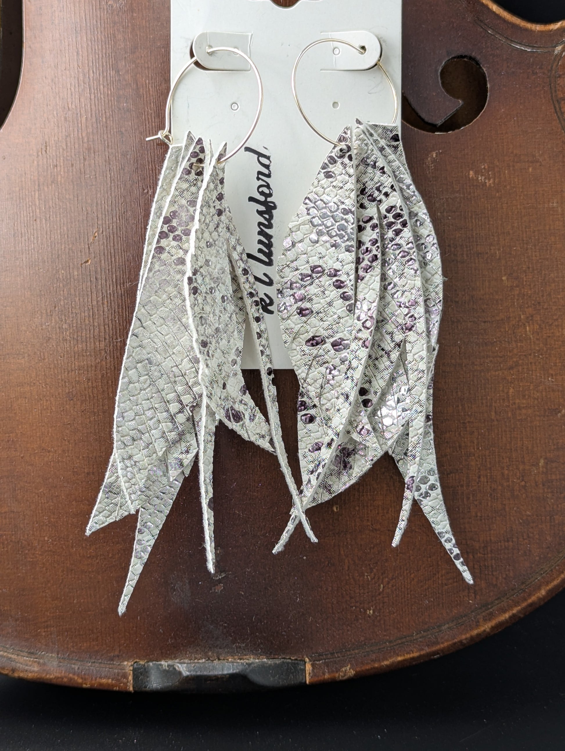 Vegan leather earrings. White, black and silver in feather shapes on delicate gold hoops. 5 inches in length