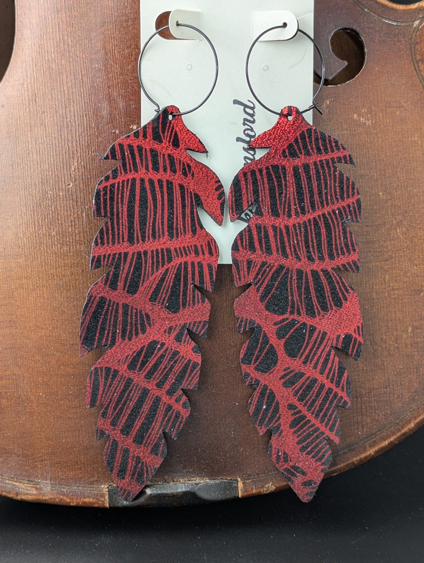 Leather feather shaped earrings, black and shiny red with black hoops. 5.5 inches long