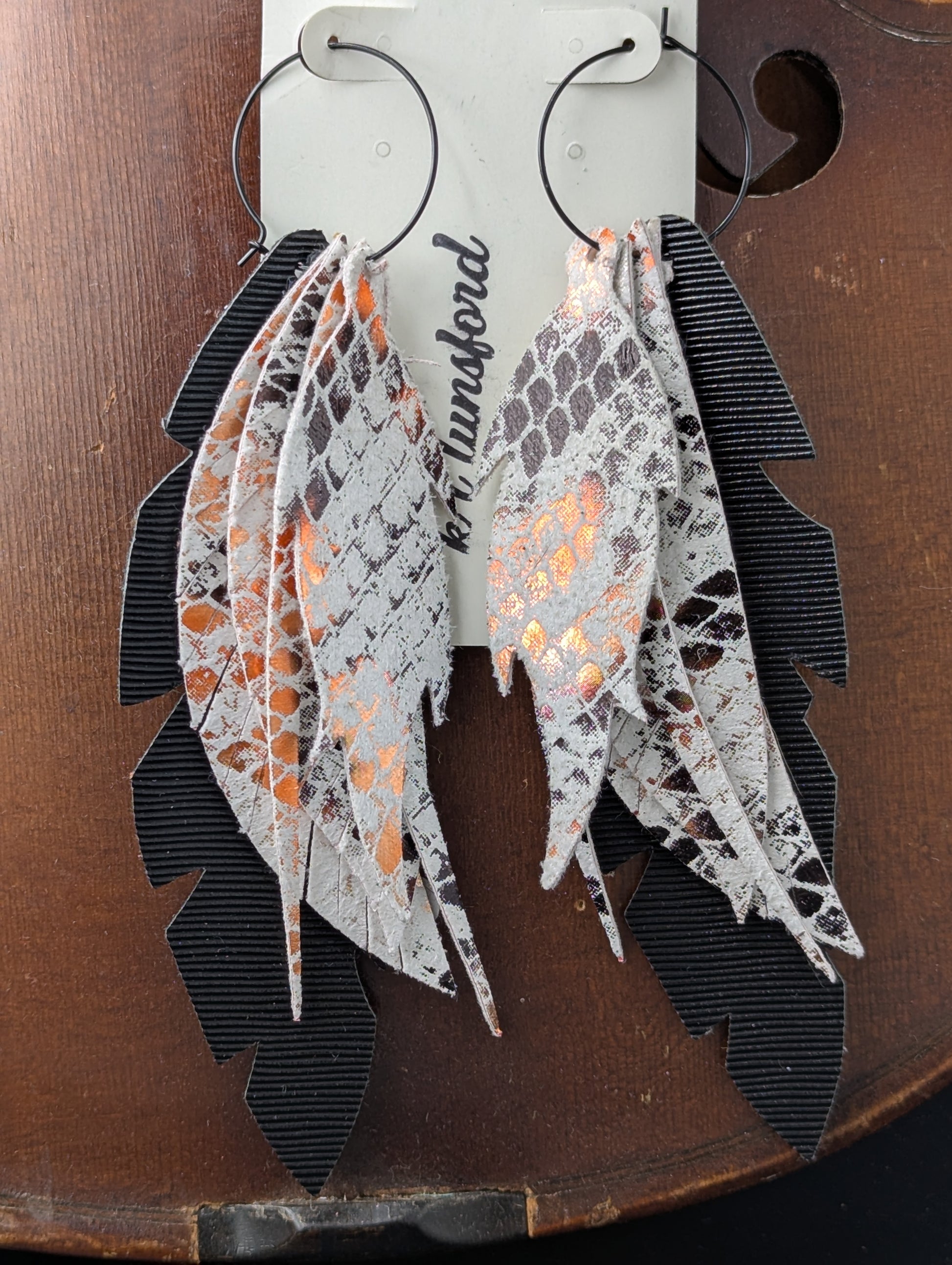 Vegan leather leaf-shaped earrings. Black, white and bronze with black hoops. 5 inches long.