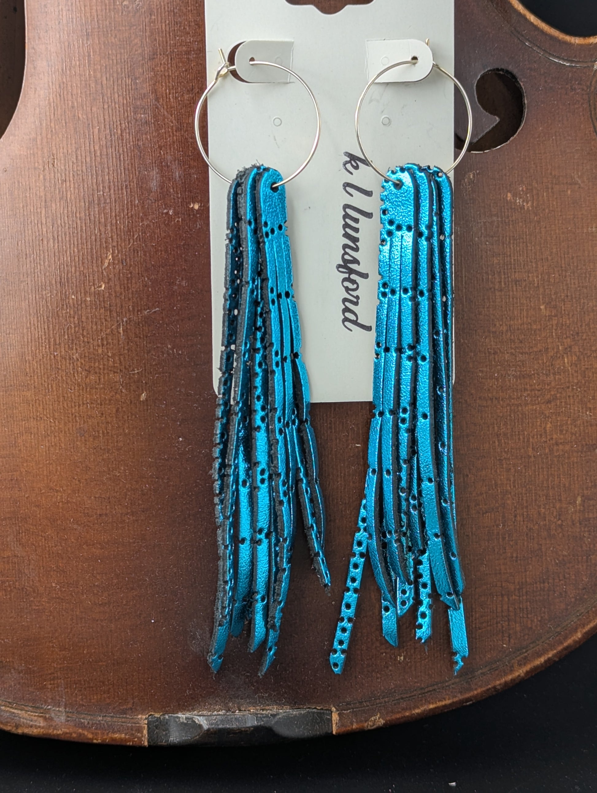 Leather earrings. Metallic turquoise with delicate holes on gold hoops. 5 inches long.