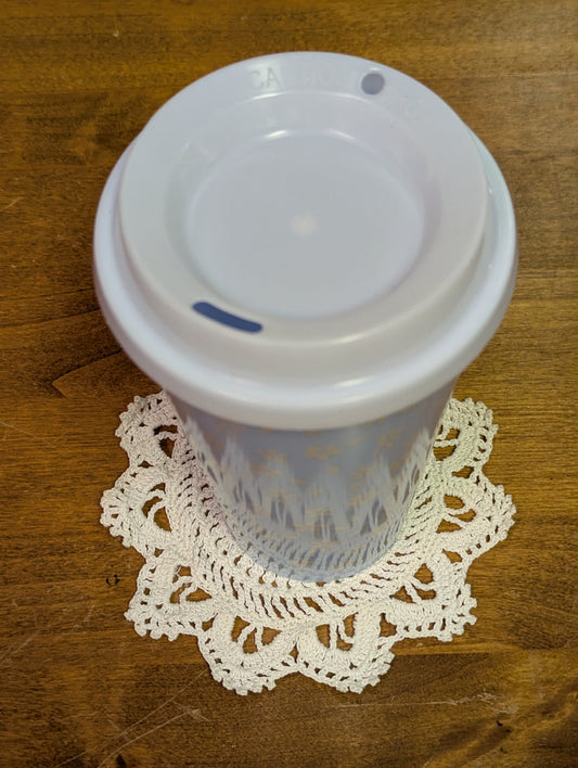Crochet coaster with a fun flower style motif, and a mug for example