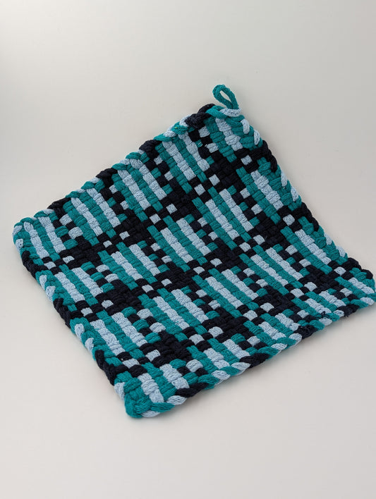 Hand woven trivet in shades of teal, navy, and gray